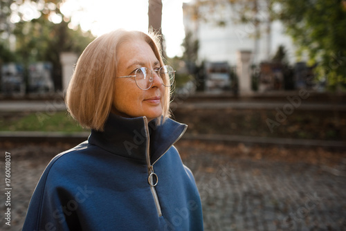 Smiling senior woman 55-60 year old wearing glasses outdoors. Stylish middle age female.