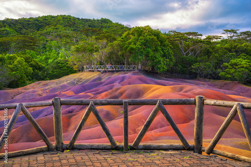 Wooden deck overlooks the vibrant, multicolored sand dunes at Chamarel Seven Colored Earth Geopark with tropical rain forest in the background, Mauritius, Africa.
