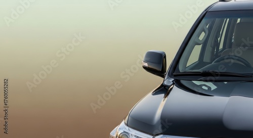Partial view of a sleek black suv against a graduated beige background