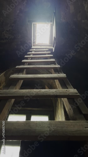 Climbing a ladder to the roof with light from the sky vertical video