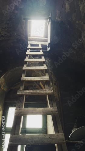 Climbing a ladder to the roof with light from the sky vertical video