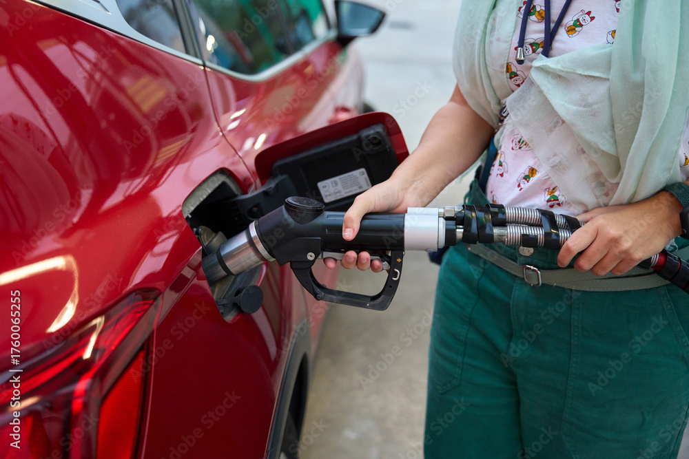 Fototapeta premium Person refueling car at gas station with fuel pump oil and gas price crisis