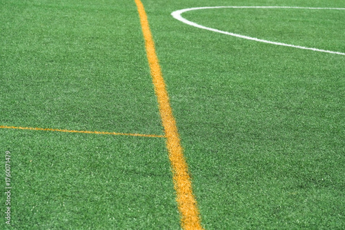 Green synthetic grass, artificial turf sports field with yellow and white lines.