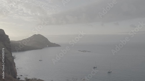 Wide shot of anchored sailboats off Madeira Portugal coast near arid hills at sunset (SLOG3)