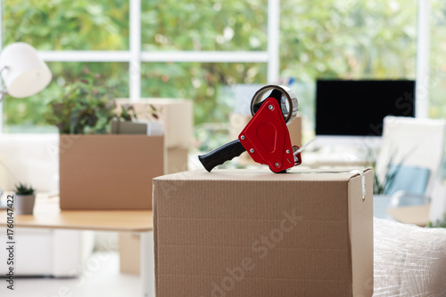 Fotografie Dispenser with adhesive tape on cardboard box in office, closeup with space for text
