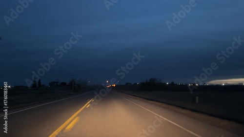 Point of view footage of a vehicle driving down an eerie unlit highway at night in rural Alberta, headlights revealing the lonely road ahead through fog and shadows, cinematic travel atmosphere.