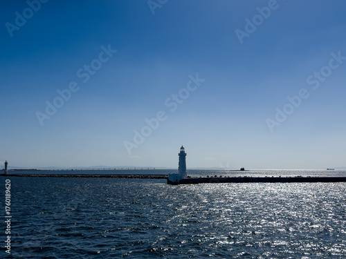 A submarine on the surface of the ocean with sparkling seas and a lighthouse in the foreground