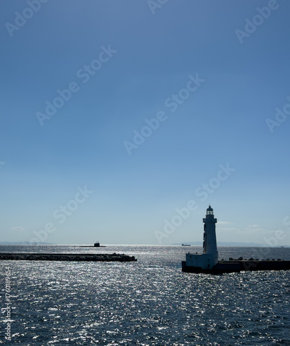 A submarine on the surface of the ocean with sparkling seas and a lighthouse in the foreground