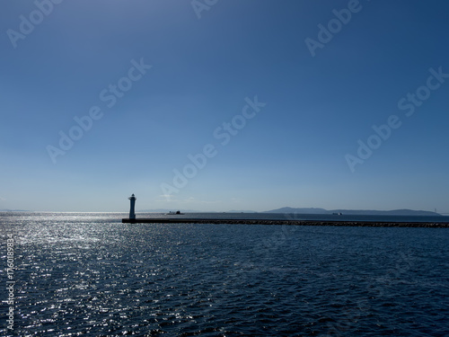 A submarine on the surface of the ocean with sparkling seas and a lighthouse in the foreground