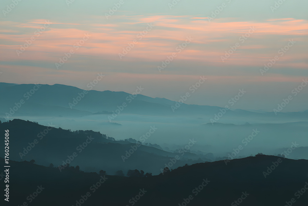 Fototapeta premium Mountain Serenity: The tranquil mountain scape unfolds with layers of rolling hills draped in a soft, ethereal mist, kissed by the gentle blush of the sunrise. An invitation to calm, peace.