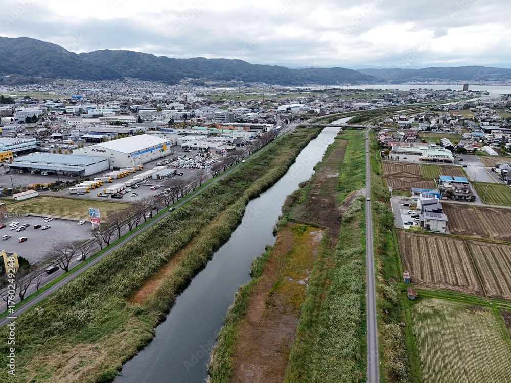 Fototapeta premium A city with a river running through it. The river is surrounded by a green area. The city is full of buildings and cars