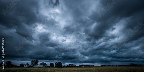 Dramatic storm clouds gather ominously over a rural landscape, hinting at approaching weather changes and raw natural power.