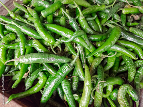 Fresh green chili peppers stacked in bulk. Green chilies for culinary seasoning and flavor. Organic green chilies harvested for spice. Fresh green peppers for sale at the market
