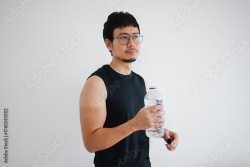 Asian fitness man enthusiast taking a moment to hydrate properly after completing their workout isolated over white background.