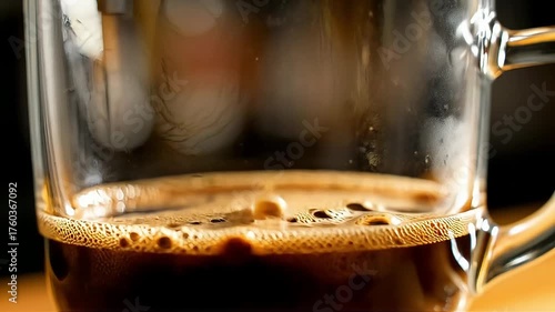 Pouring rich, dark coffee into a clear glass mug for a delicious morning pick-me-up - a perfect start to your day with this caffeinated beverage