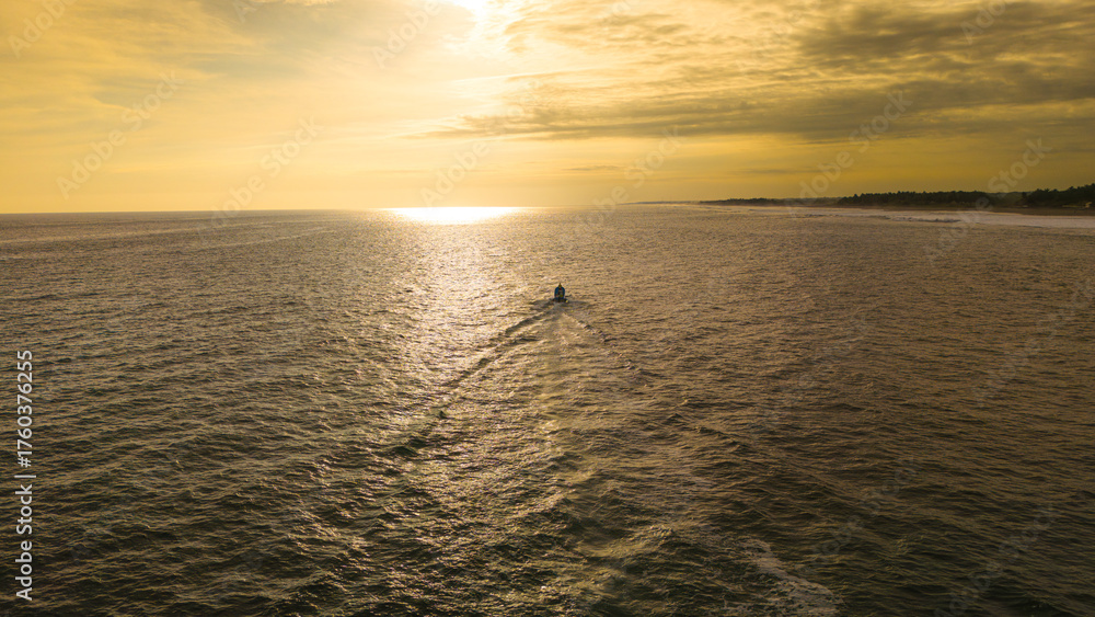 Obraz premium Pescadores en una lancha en El Salvador Navegando hacia el horizonte Amanecer o atardecer (luz dorada) Vista aérea o tomada con dron Océano Pacífico Sentido de calma, libertad, trabajo y conexión