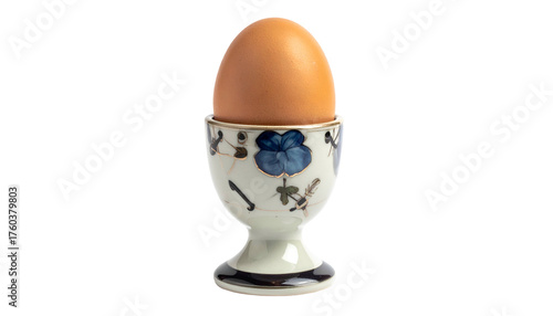 Brown egg standing tall in floral-patterned egg cup, isolated