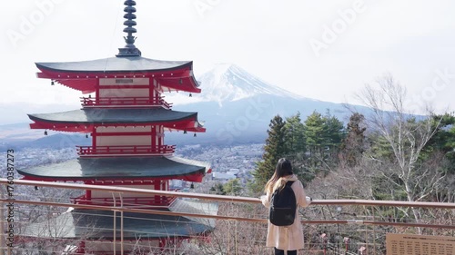 Happy Asian woman enjoy outdoor lifestyle travel at red Chureito Pagoda with Mt Fuji covered in snow background in winter day. People travel Japan landmark famous place and season change concept.