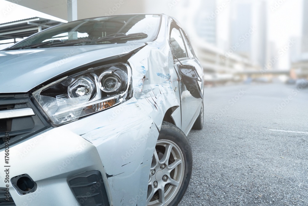 Fototapeta premium Front side view of a car with visible damage and dents after an accident. Vehicle crash, insurance claim, road safety, and car repair concept.