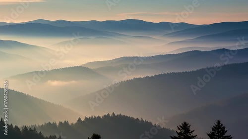 Serene mountain view with layers of peaks shrouded in mist and fog under a softly lit sky