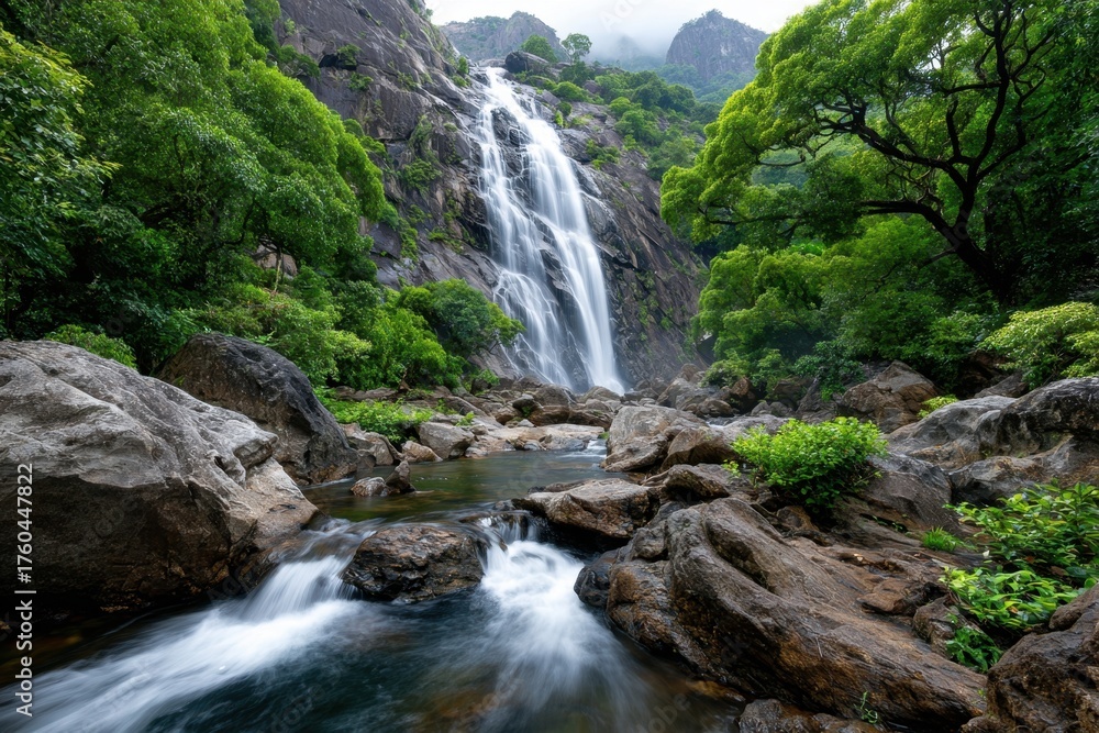 Fototapeta premium Waterfall cascading down rocky cliffs in lush green forest