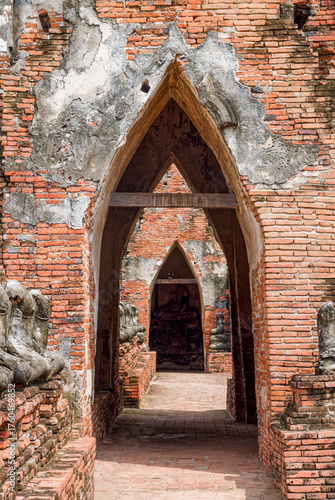The ruins of the Phra Rabieng (gallery or cloister) of Wat Chaiwatthanaram in Ayutthaya, Thailand. The brick wall is lined with the bases of seated Buddha statues, all decapitated by the Burmese.