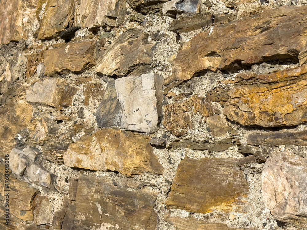 Fototapeta premium Rustic stone wall with weathered texture and natural patterns