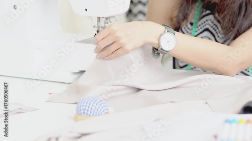 The seamstress is sewing a dress. Young woman sewing while sitting at her working place.