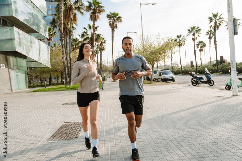 Obraz premium A male athlete is talking to a female athlete running next to him and smiling