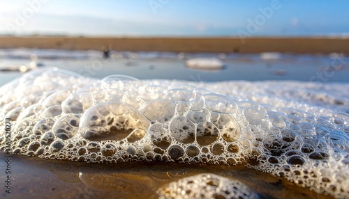 Fototapeta Naklejka Na Ścianę i Meble -  Close-Up of White Sea Foam Bubbles on Sandy Beach