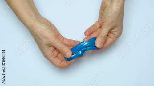 Human hands squeeze a viscous colorful slime. View from above. On a white background. Relaxation, calming down. 
