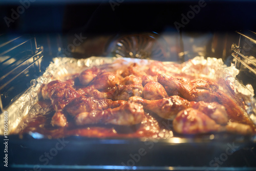 Cooking chicken at home in an electric oven. View of cooked chicken legs through the glass of an electric oven.