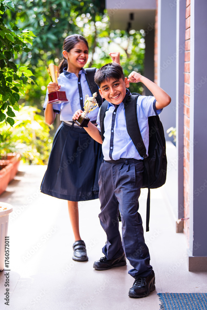 Obraz premium Indian School Kids in Uniform Flaunting Trophy Proudly While Standing Outside and Looking at Camera