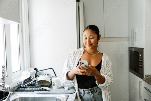 Foto A woman is standing and typing on the phone while smiling