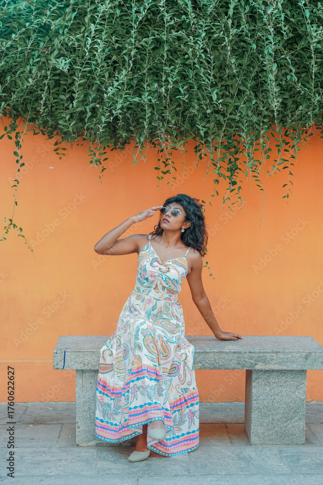 Obraz premium A woman is sitting on a bench wearing a colorful dress