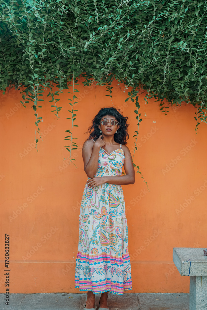 Fototapeta premium A woman is standing in front of a wall with a green plant growing on it