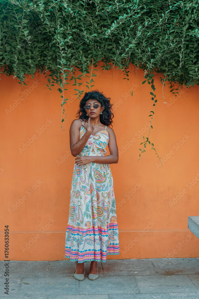 Fototapeta premium A woman in a white dress stands in front of a wall with green vines
