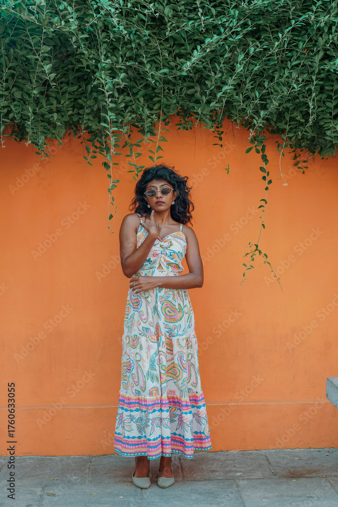 Obraz premium A woman in a colorful dress stands in front of a wall