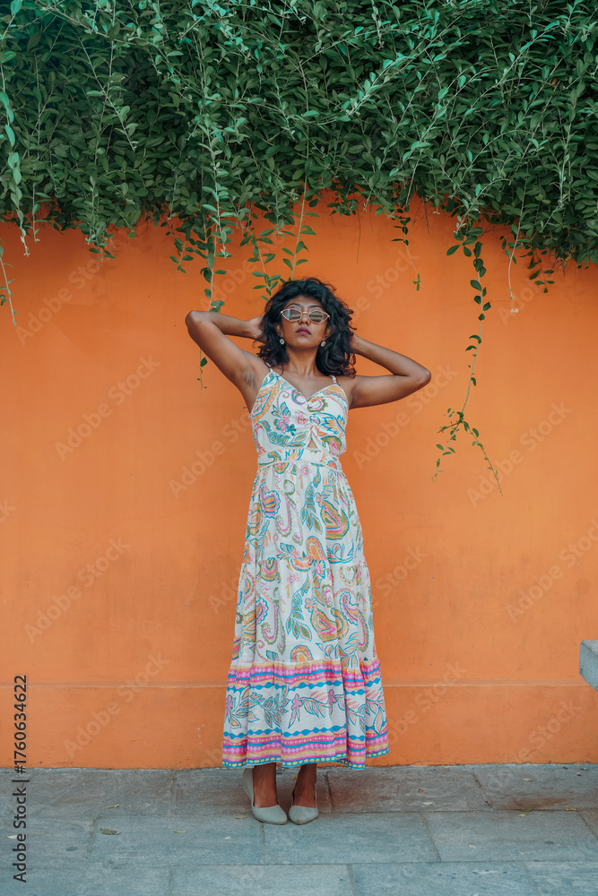 Obraz premium A woman in a long dress stands in front of a wall with green vines