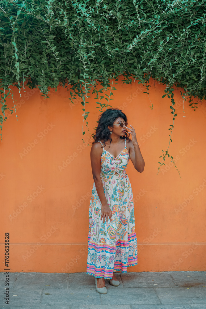 Obraz premium A woman in a colorful dress stands in front of a wall