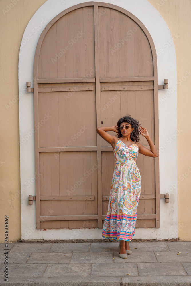 Fototapeta premium A woman in a white dress stands in front of a building with a doorway
