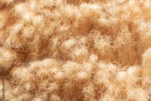 Macro close-up of soft beige fabric fibers, fluffy texture with fibres and nap in warm lighting
