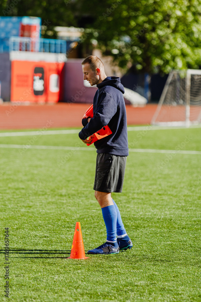 Fototapeta premium A man walks and carries soccer cones