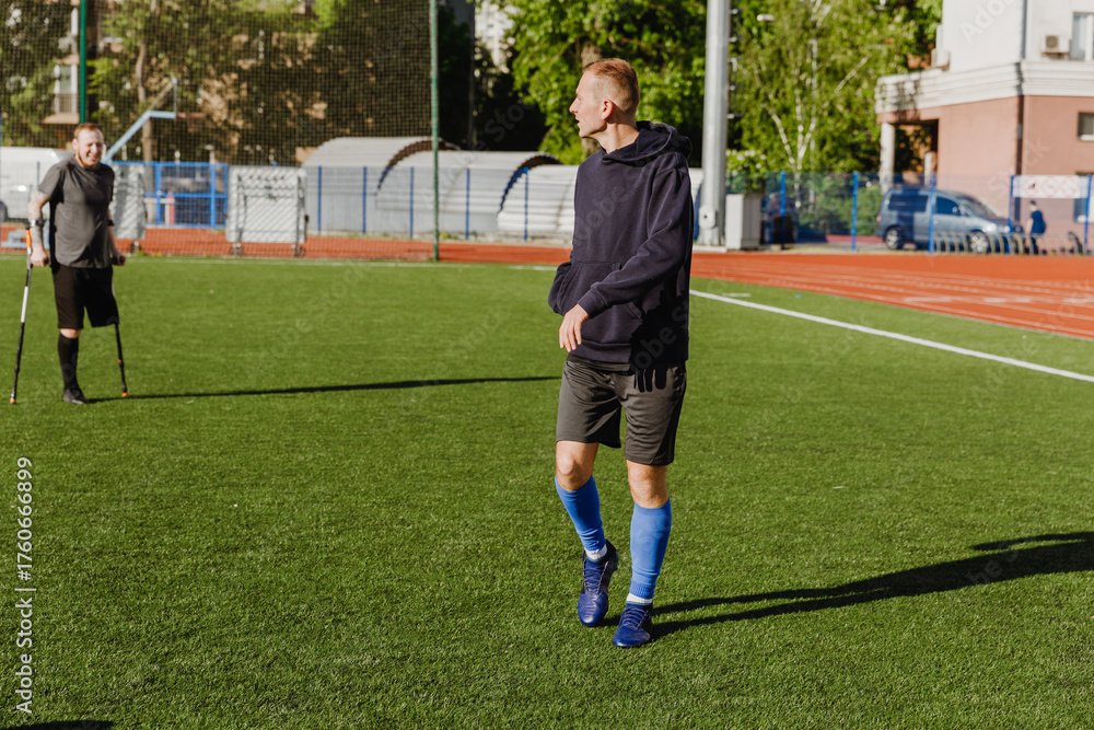Fototapeta premium A male player walks and looks towards a male player who is leaning on crutches
