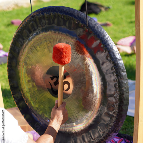 Obraz na plátně person playing the gong during a yoga session and sound bath in nature