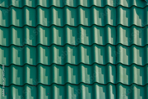 Close-up view of textured green roof corrugated painted green steel sheets cold rolled in a form of roof tiles.