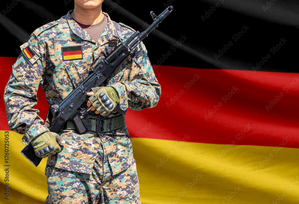 Fototapeta premium Germany flag with soldier in military uniform holding assault rifle in front of it
