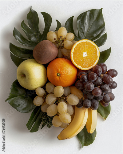 Fresh fruits arranged beautifully on green leaves create vibrant and healthy display. This colorful assortment includes bananas, grapes, oranges, and more, evoking sense of freshness and vitality