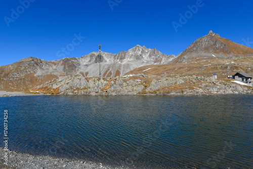 High mountain panorama in late summer, early autumn, with green and yellow larches, blue sky, in the Swiss Alps.