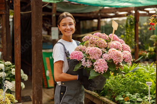 A cheerful and talented florist proudly showcases vibrant, colorful hydrangeas in a beautiful garden setting